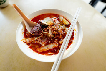 Close up of a bowl of hokkien mee or prawn noodle in prawn-based soup which is popular in Malaysia and Singapore. Toppings include eggs, meat slice and tofu.