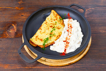 Delicious savory omelette served with creamy sauce on wooden table