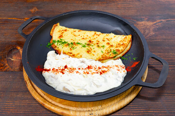 Savory omelet served with creamy yogurt on wooden table
