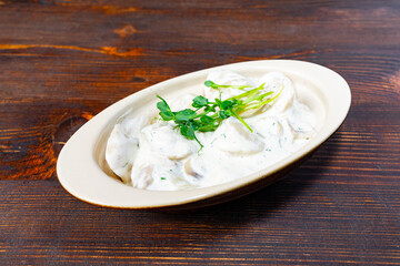Creamy dish topped with fresh greens on wooden table
