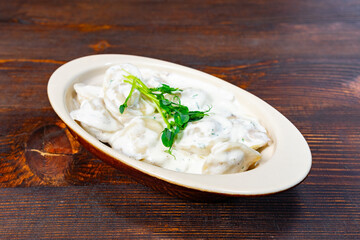 Delicious dumplings served in creamy sauce on wooden table