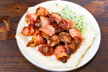 Savory dish of bacon-wrapped meat served on a plate with greens