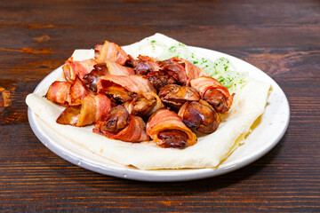 Delicious bacon-wrapped delicacies served on a wooden table