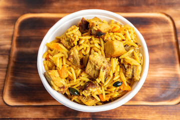 Flavorful chicken biryani served in a white bowl on a wooden table