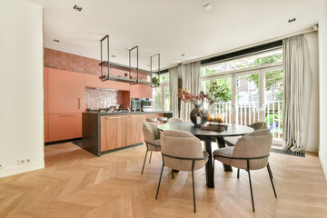 A stylish modern kitchen showcases sleek cabinetry and an elegant dining setup, bathed in natural light from large windows.