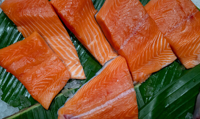Fresh raw filleted salmon pieces on banana leafs.