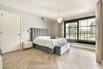 A stylish and modern bedroom featuring minimalist decor, large windows allowing natural light, and a comfortable bed with elegant furnishings.