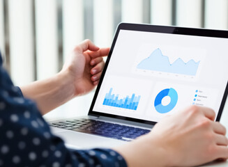 person's hands using a laptop displaying blue charts and graphs