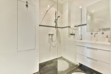 Stylish bathroom featuring a glass shower enclosure, sleek modern fixtures, and elegant white tiles, creating a clean and contemporary aesthetic.