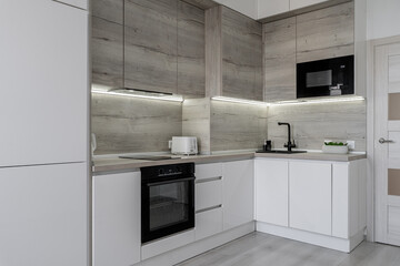 Modern kitchen with cabinets and induction on counter, built-in oven, microwave. kitchen with white...