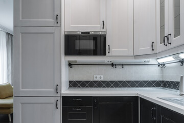 interior of modern apartment. design of built-in kitchen with white cabinets and black countertops....