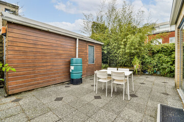 A serene outdoor space featuring a wooden shed, a dining table with chairs, and lush greenery. Ideal for gatherings and relaxation in a contemporary setting.