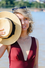 Girl with glasses puts on a hat while relaxing on the beach. Summer mood.