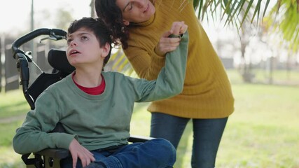 Loving mother assisting disabled son in wheelchair at park