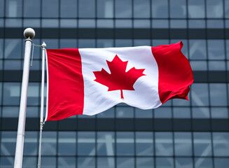canadian flag waving proudly in front of a modern building