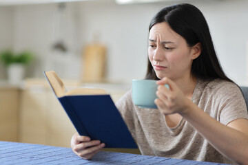 Sad asian woman reading book and drinking