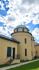 two adjacent pale-yellow brick buildings with domed roofs under a bright summer sky