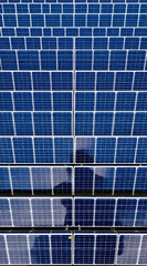 aerial view of numerous blue solar panels forming a geometric grid