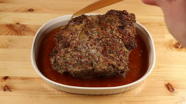 A juicy roasted pork resting in its own flavorful juices, carefully basted to enhance its succulence and golden-brown color.