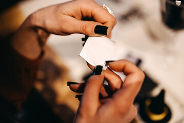 Fototapeta premium Hands holding a blank small piece of paper with manicured nails with black nail polish.