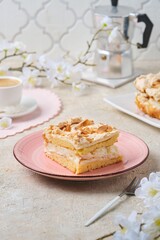 Norwegian dessert, sliced best cake with meringue, almonds and custard on a pink dessert plate on a light concrete background. Norwegian cuisine.