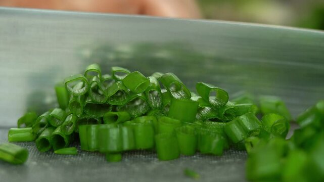 Close up of hands cut fresh green onions with kitchen knife. Cooking food with greens. Greens, vegetables