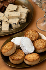 A close-up of traditional Spanish sweets, including polvorones and mantecados with sesame alongside turron