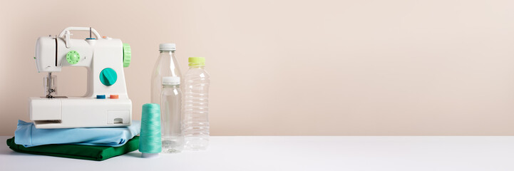 Plastic bottles, sewing machine, folded t-shirts web banner, copy space, concept of clothes made from recycled plastic