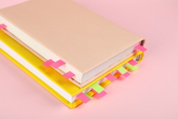 Books with colorful tabs on pink background, closeup