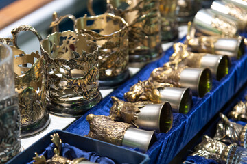 Decorative metal cup holders displayed at a market in summer