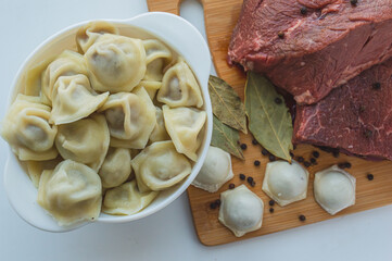 A piece of beef meat and beef dumplings on a kitchen board. A banner with meat products marbled beef peppercorns and bay leaves. High quality photo