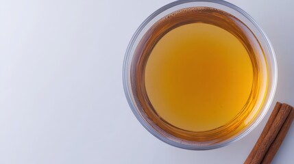 Warm Amber Liquid in Glass with Cinnamon Stick on White Background