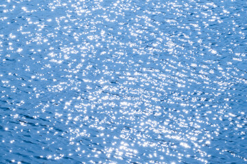 abstract background of blue water surface with sun rays and sparkles