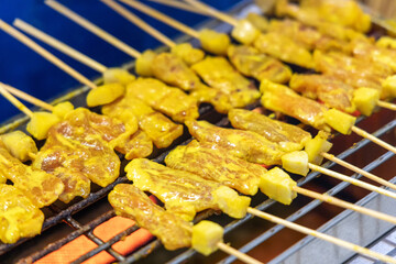 Grilling Thai style pork satay on grill mesh. Pork satay stick local street appetizer or dessert popular in south east asia recipe.