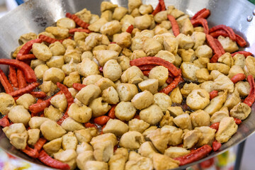 Deep frying meatballs and sausage in pan by oil. Local Thai street food and appetizer.