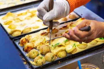 Making takoyaki balls filled on a hot pan snacks and local street food in japan festival.