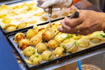 Making takoyaki balls filled on a hot pan snacks and local street food in japan festival.
