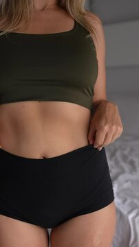 Young blonde woman pulls in her stomach to look slimmer. Relatable body image insecurity moment. Vertical faceless video showing self-conscious behavior and hidden body pressure
