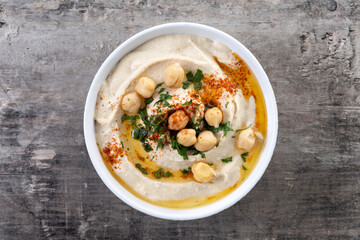 Chickpea hummus with olive oil, parsley and paprika in bowl on wooden table