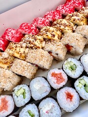 An assortment of different sushi rolls with vibrant colorful toppings and fresh ingredients, displayed in a close-up view.