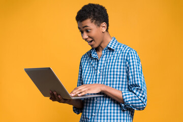 Happy Afro American teenager working with laptop.