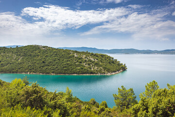 The sea coast of southern Dalmatia in Croatia, Europe. Scenic coastal view: Lush green island meets turquoise waters under a partly cloudy sky. Perfect for nature lovers and exploration.