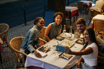 Group of friends taking photo of themselves while dining at restaurant in Lisbon