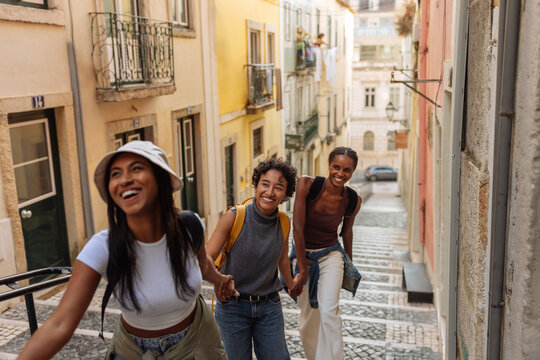 Three tourists holding hands are walking down the stairs of lisbon