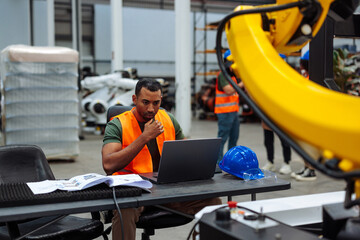 Engineer programming automated robotic arm in factory