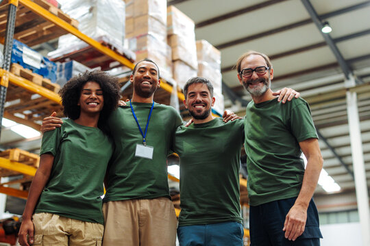 Warehouse workers smiling and embracing teamwork in distribution center