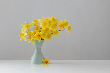 yellow spring flowers in green vase on white background