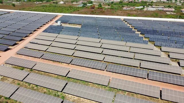 Aerial low panning overview of inverters and very contrasting dirty and clean solar panels of utility power plant