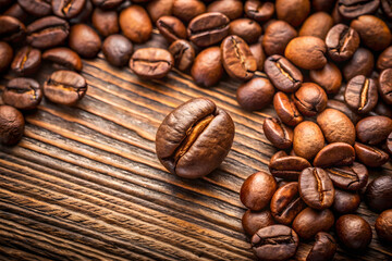 Naklejka premium Fresh coffee beans scattered on wooden table create rich aroma