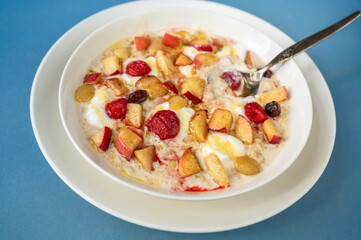 Oatmeal porridge with strawberry, apple, almond and nut, honey and butter in white plate